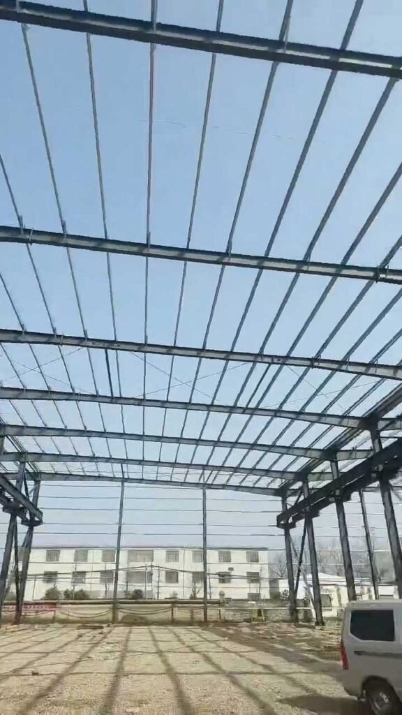 Vista frontal de las conexiones empernadas y la modulación de las columnas en un almacén de estructura metálica en construcción.