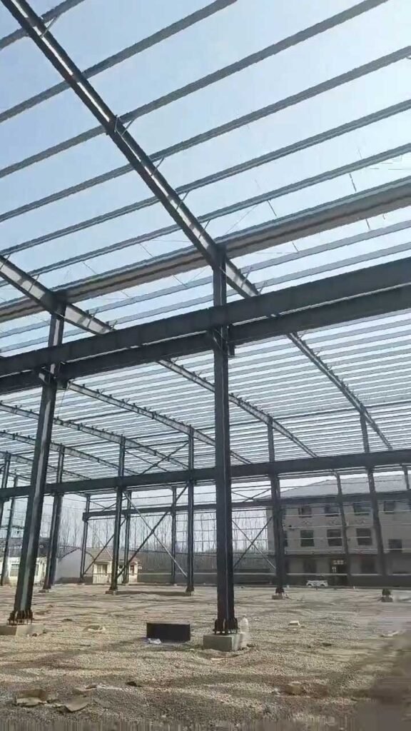 Sistema de vigas principales y correas de techo instaladas en un almacén de estructura metálica industrial.