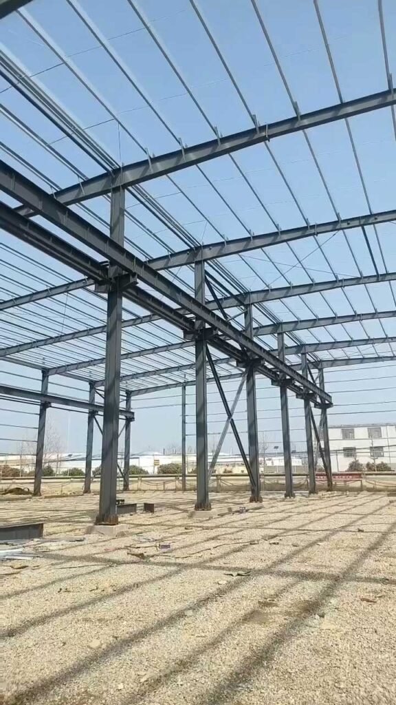 Esqueleto metálico de un edificio prefabricado PEB con columnas perfil H ancladas a bases de hormigón.