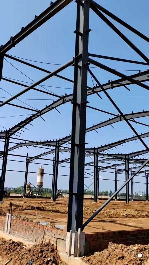 Detalle de columnas perfil H y conexiones empernadas en la fase inicial de montaje de un almacén PEB de acero.
