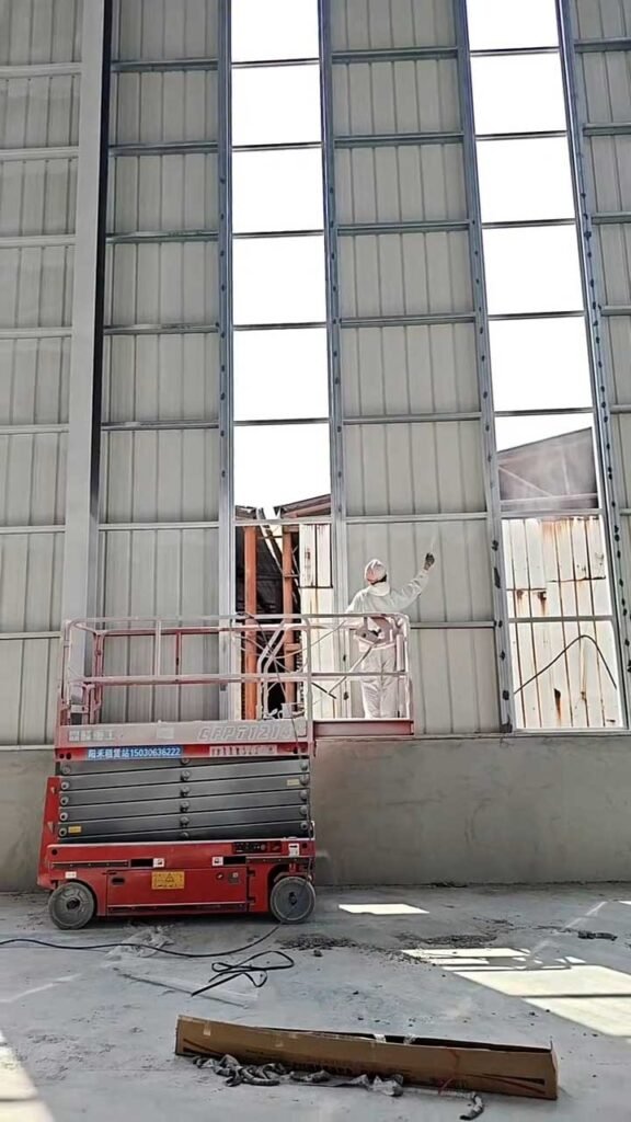 Interior de galpón metálico con arriostramientos de acero, manta aislante y tambores de recubrimiento en piso