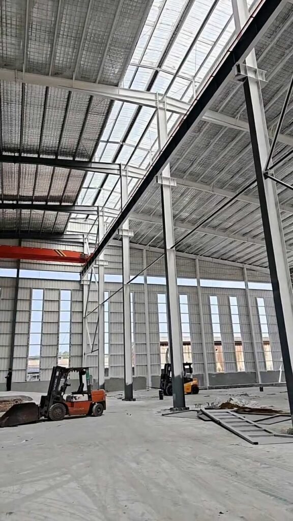 Plataforma elevadora trabajando en el detallado de la estructura secundaria y cerramiento de un almacén prefabricado