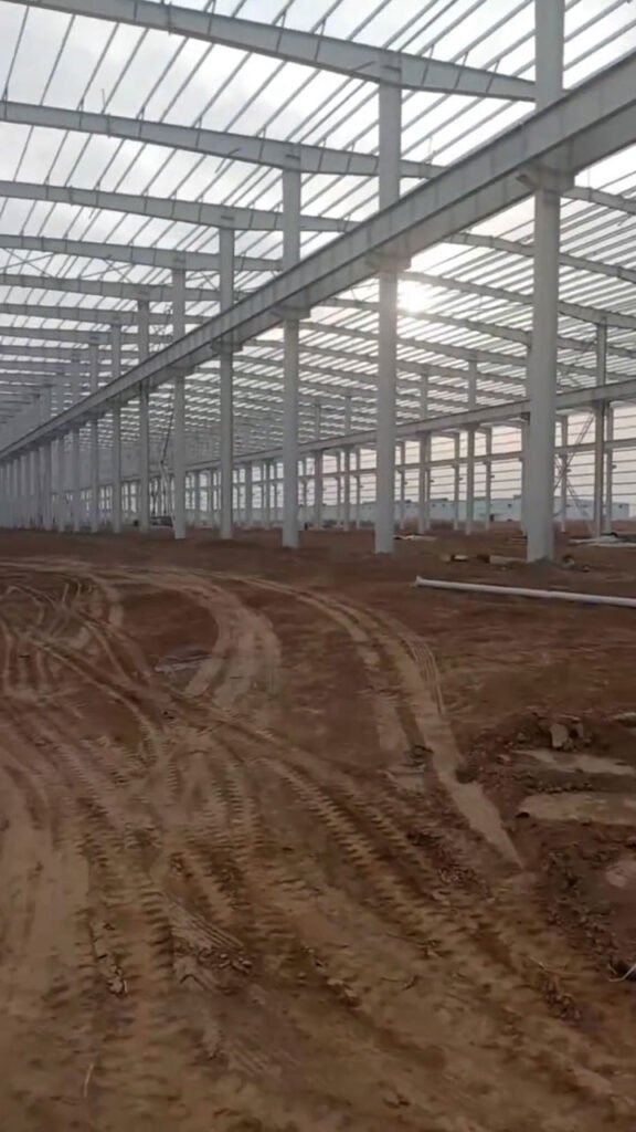 Secuencia de columnas de perfiles H y cerramientos laterales en construcción de galpón industrial prefabricado.