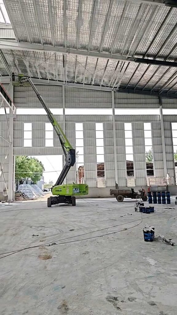 Operario en plataforma elevadora instalando aislamiento térmico en la cubierta de una nave industrial
