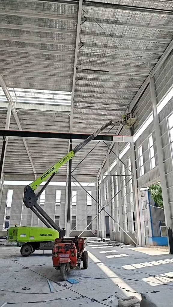 Proceso de instalación de paneles y cerramientos en un edificio de almacén con estructura metálica utilizando maquinaria de elevación