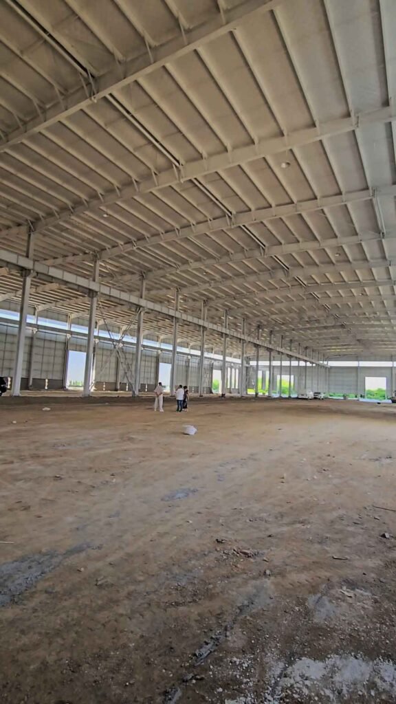 Inspección del avance de obra en un galpón metálico gigante manufacturado por una fábrica directa de almacenes metálicos en China.