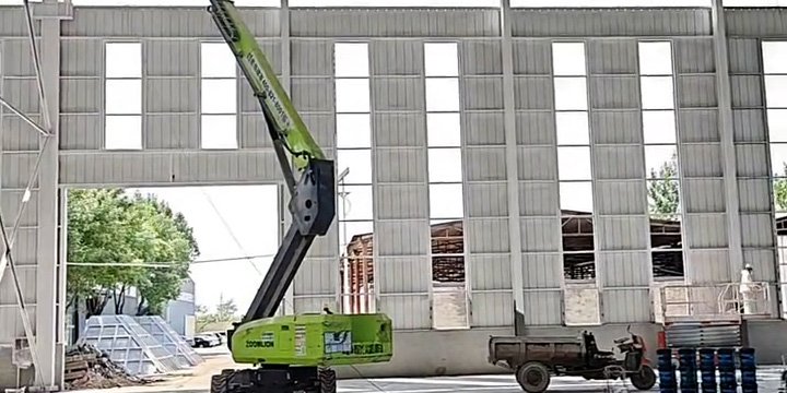 Elevador articulado realizando el montaje de cerramientos perimetrales en un galpón metálico