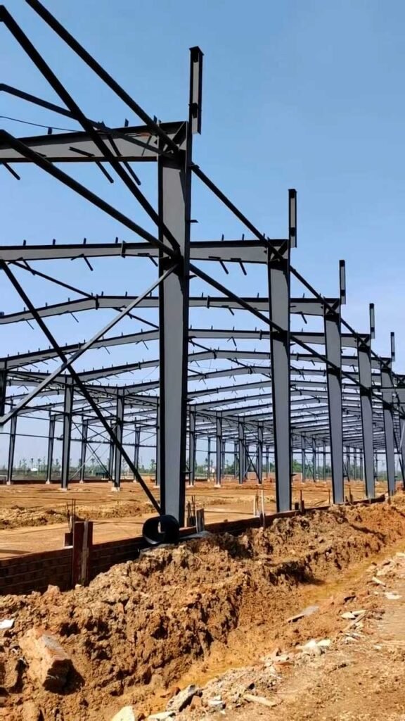 Secuencia de pórticos rígidos instalados sobre la cimentación durante la construcción de un almacén PEB de acero industrial.