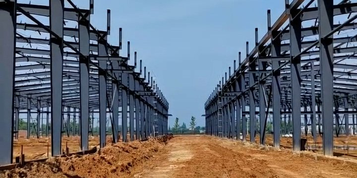 Estructura metálica principal de un almacén PEB de acero erigida sobre terreno preparado para el vertido de losas industriales.