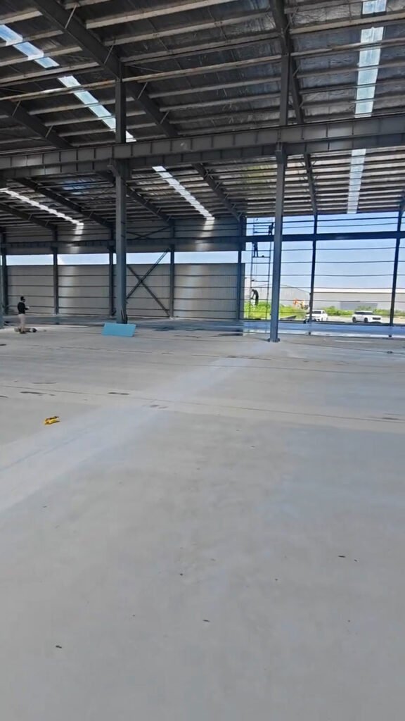 Vista en perspectiva de bodega industrial con pórticos de perfiles H.