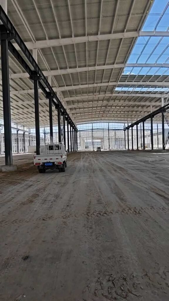 Interior view of clear-span steel warehouse framing showing roof purlins and light distribution