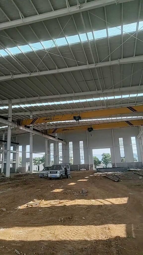 Estructura de acero de una nave industrial con columnas, vigas, arriostramientos diagonales y cubierta con franjas translúcidas