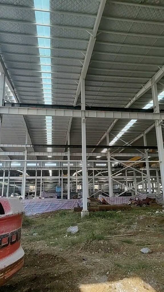 Correas metálicas, vigas de acero y paneles translúcidos en la cubierta de una nave industrial en construcción