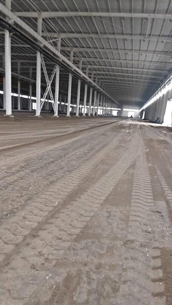 Vista longitudinal de un galpón industrial con columnas metálicas, vigas de cubierta y amplio espacio interior.