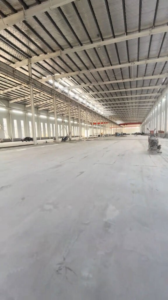 Vista en perspectiva de galpones metálicos con suelo de concreto pulido.