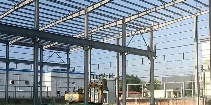 Montaje de estructura de acero para nave industrial de gran luz libre con maquinaria pesada.