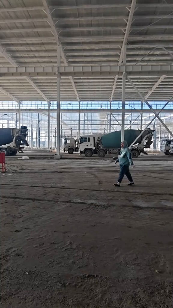 Interior en construcción de un galpón industrial con columnas de acero y cubierta prefabricada